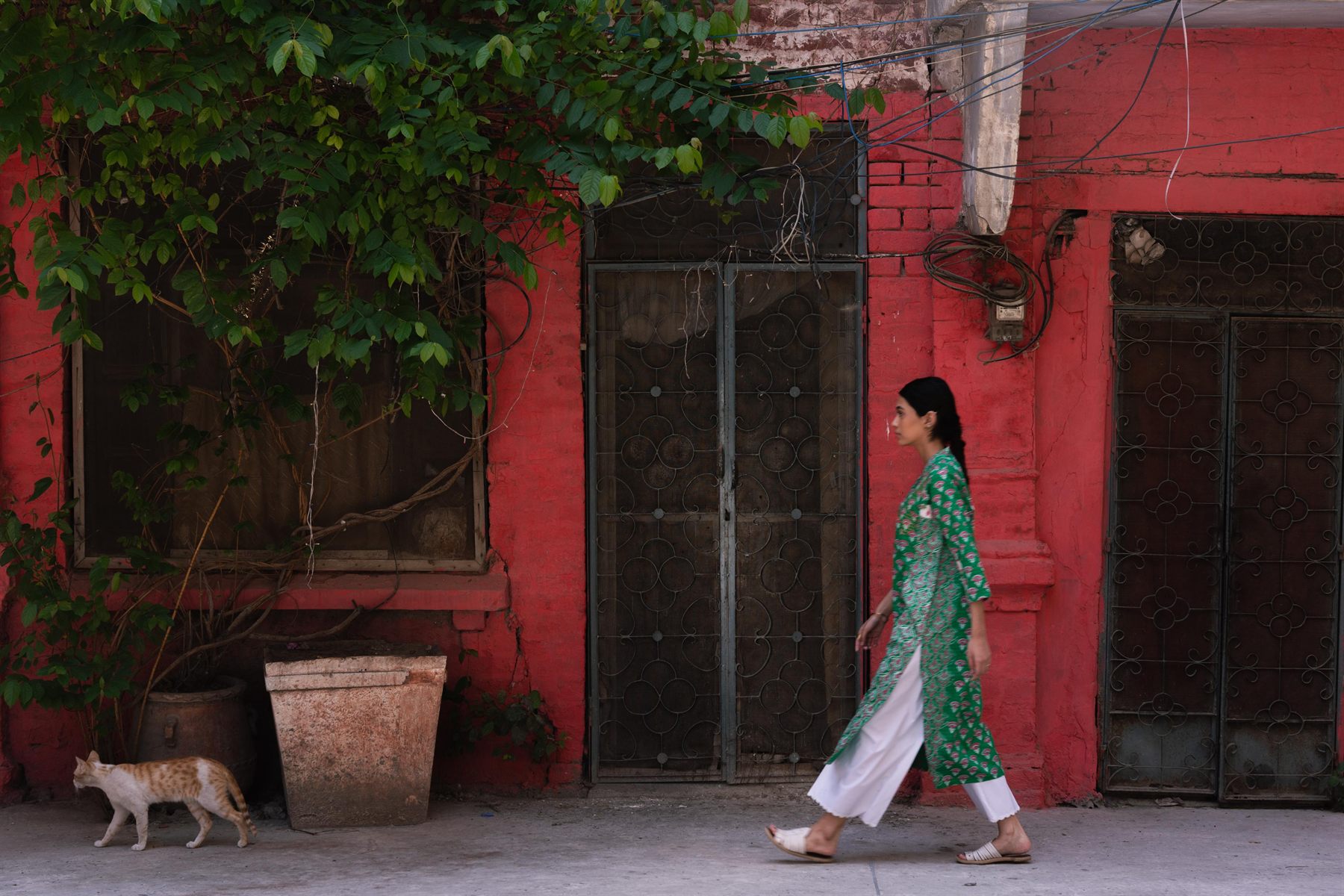Model in green walking along a red brick street