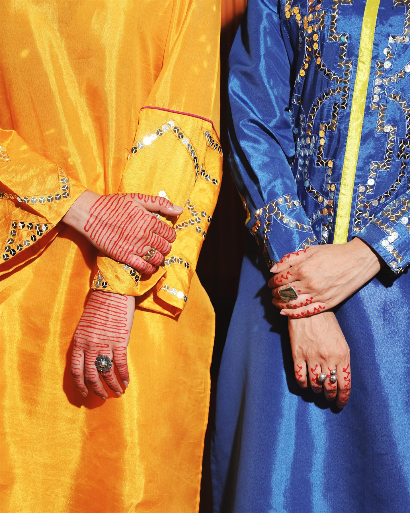 Close-up of hennaed hands against ochre and cobalt silk