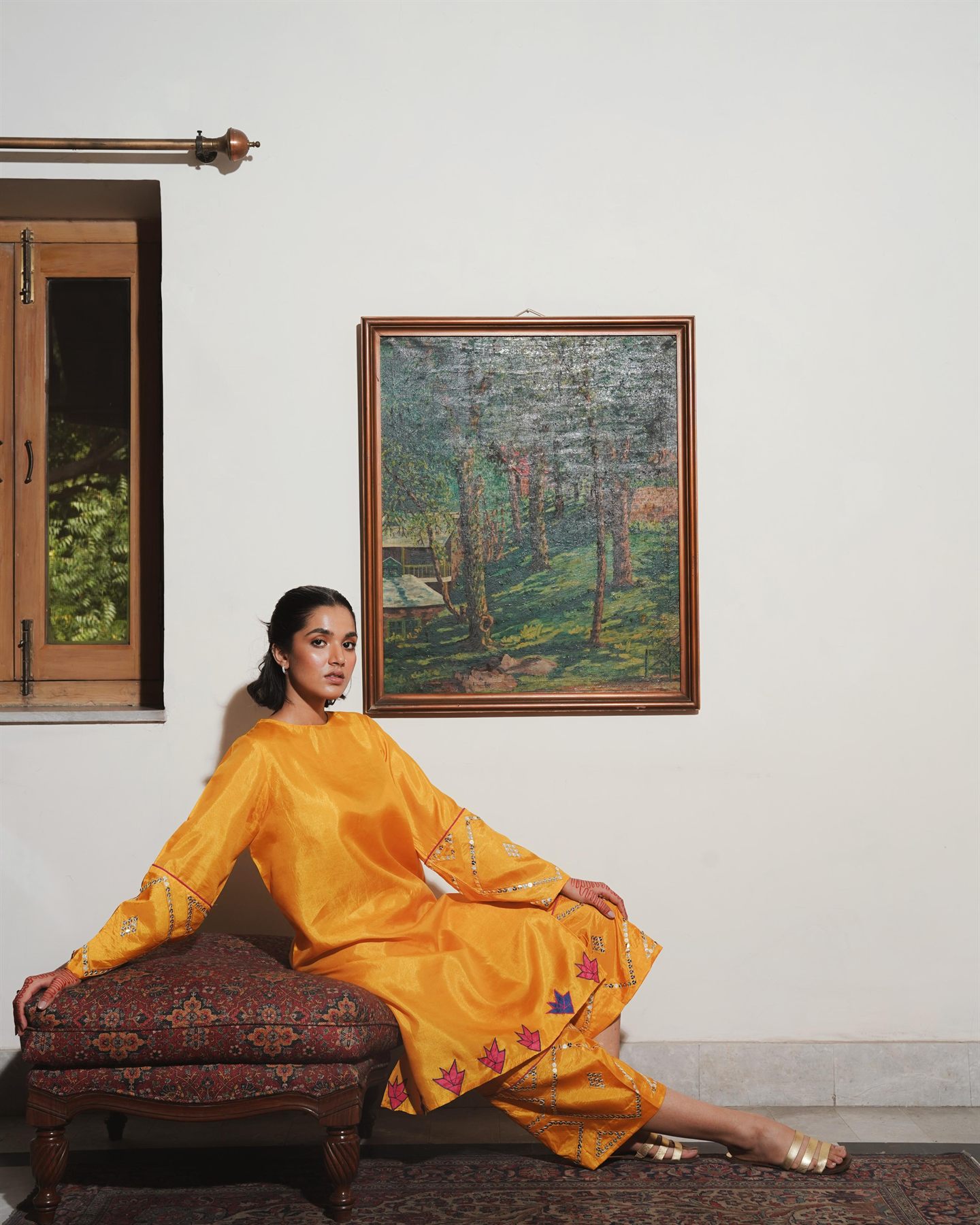 Model in an ochre silk suit reclining on an embroidered ottoman