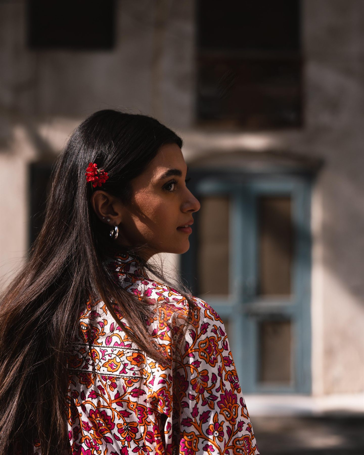 Portrait in a floral print with a red flower in the hair